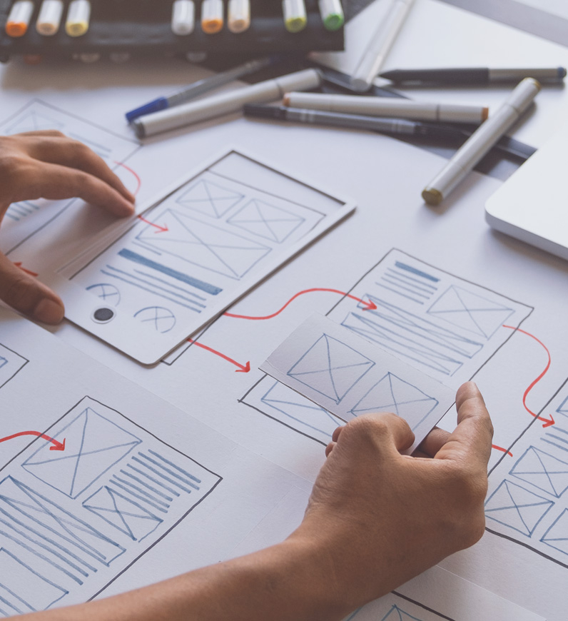 A person working on a prototypw design at a table, ensuring flawless user experience and addressing potential issues for business efficiency.