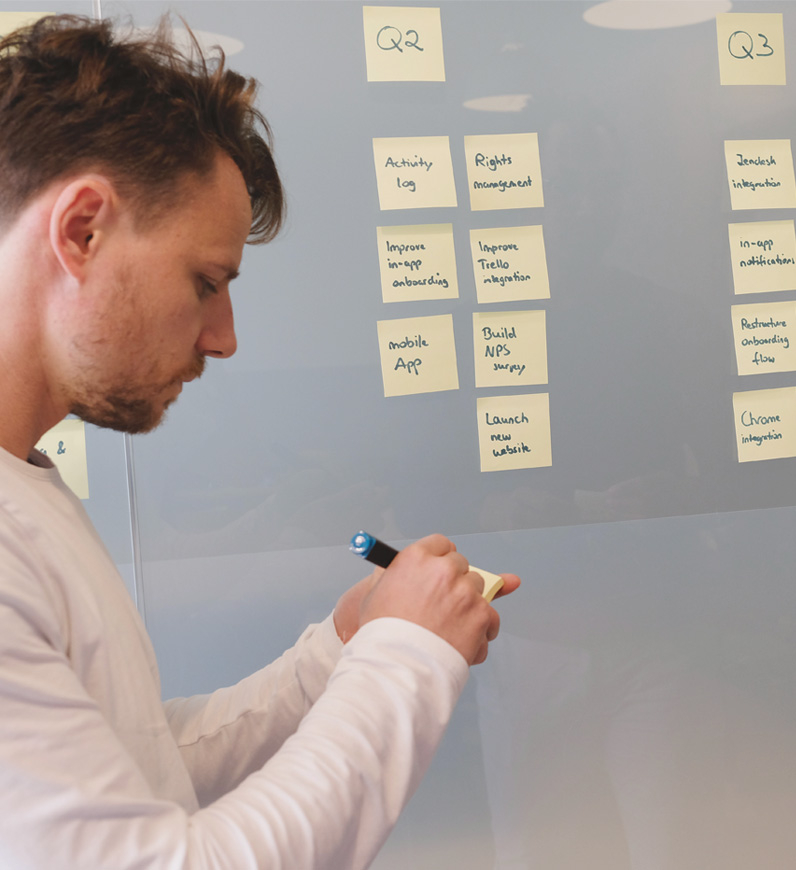 Quality Assurance expert writing on the whiteboard with sticky notes, outlining assessments and recommendations