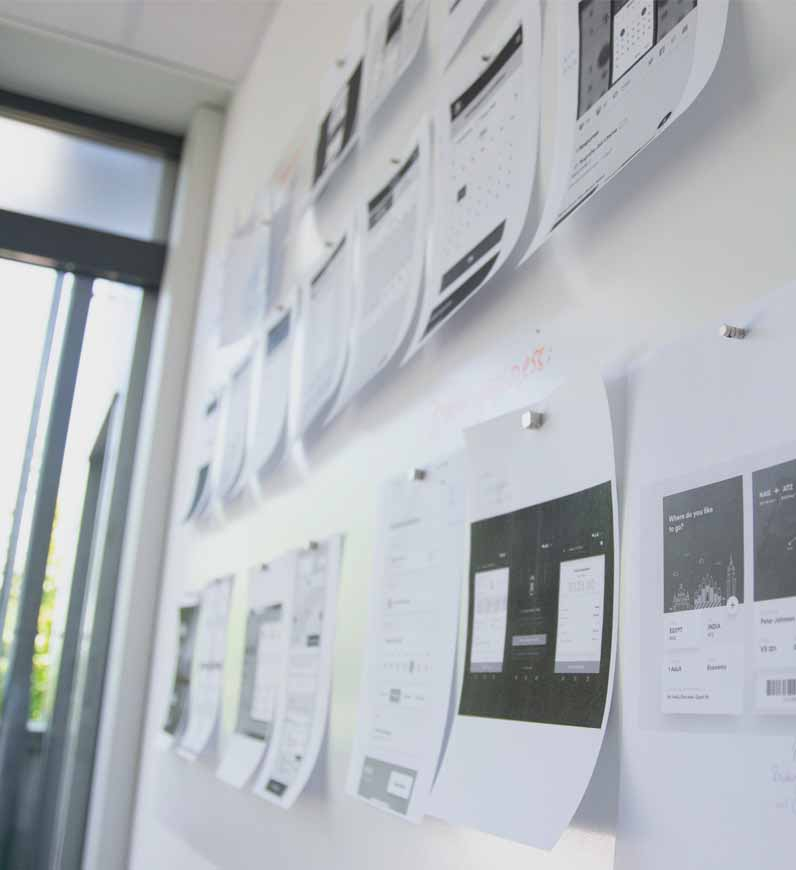 Papers scattered on white wall, representing content creation for businesses to attract, engage, and convert target audience.
