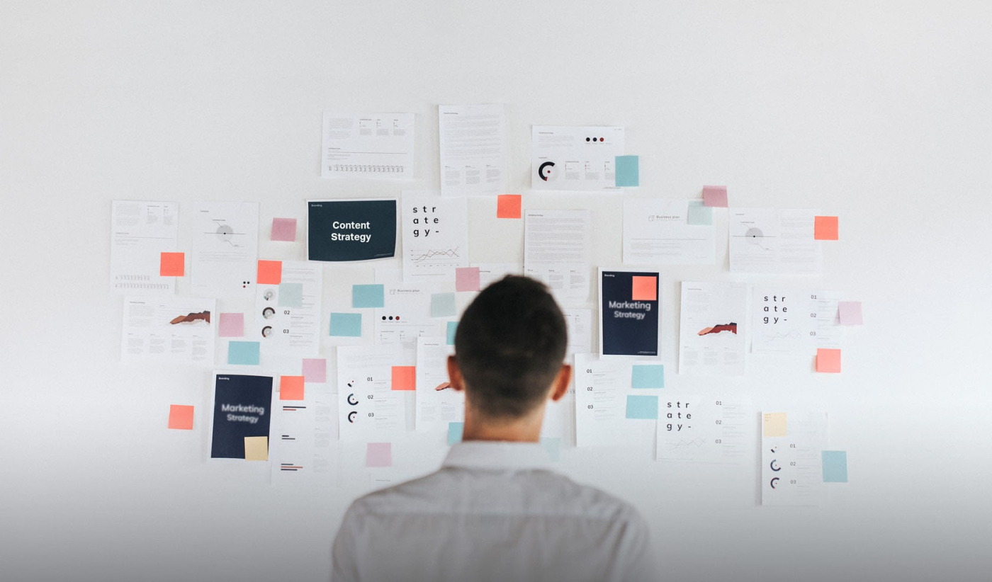 A man studying a business plan on a whiteboard, strategizing for success with a comprehensive content strategy.