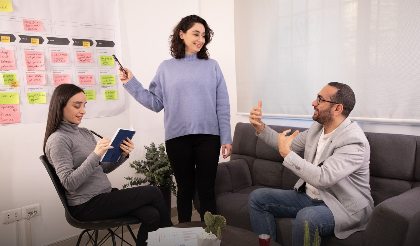 Team of UX researchers discussing customer-centric service design on a couch in an office setting
